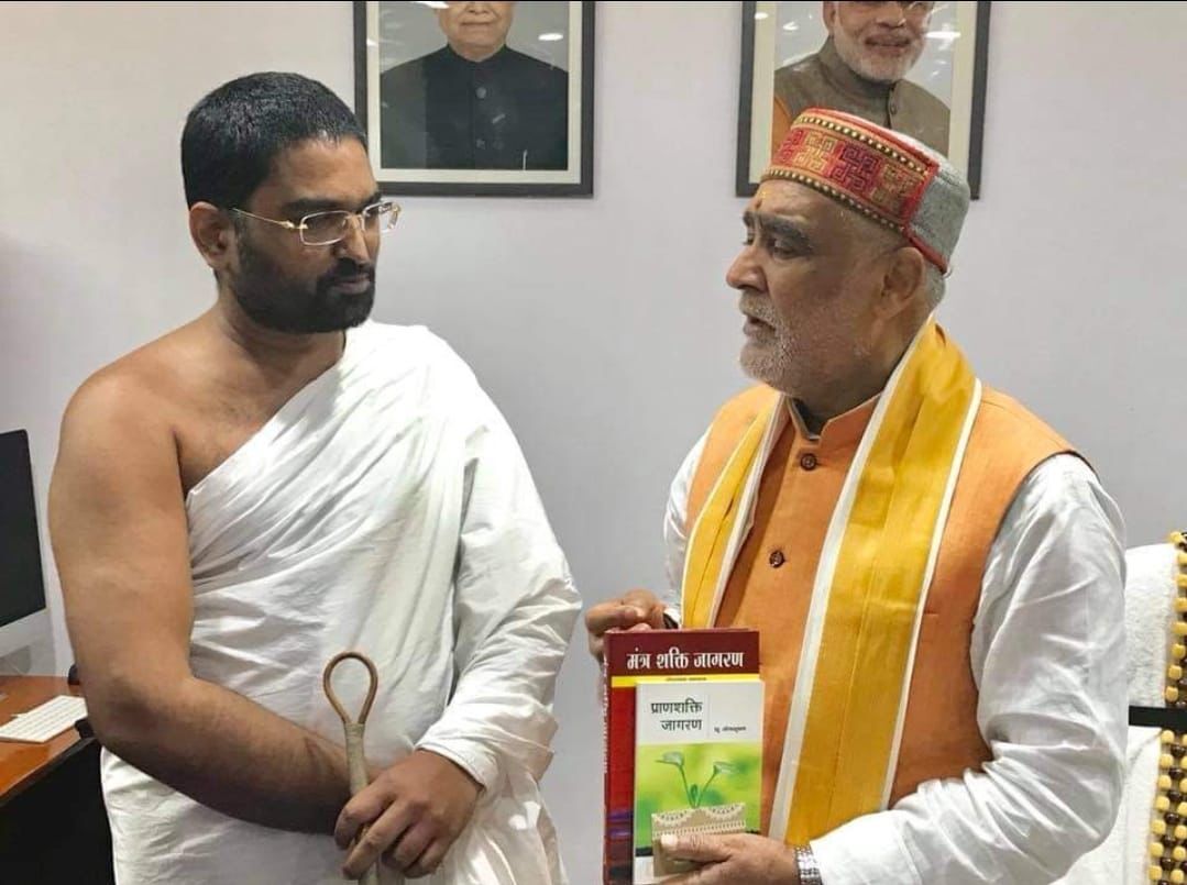 Maharaj Ji presenting publication to Union Minister with PM Modi portrait visible